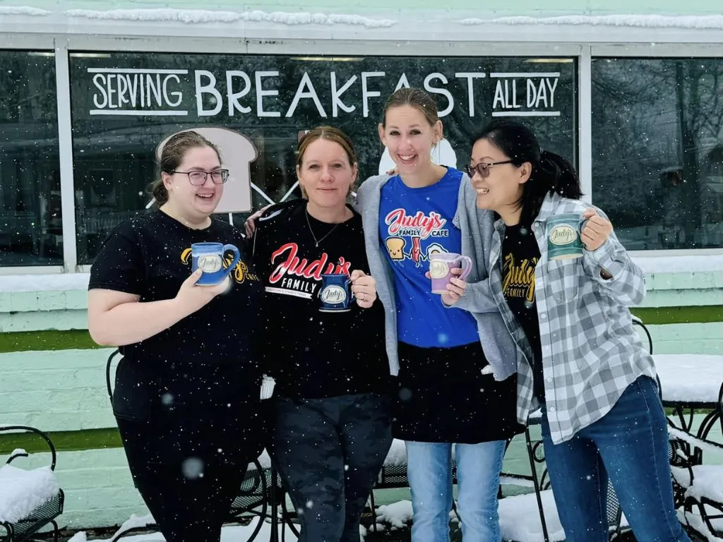 four employees by cafe building