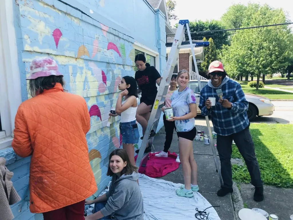 group of teens helping paint cafe building